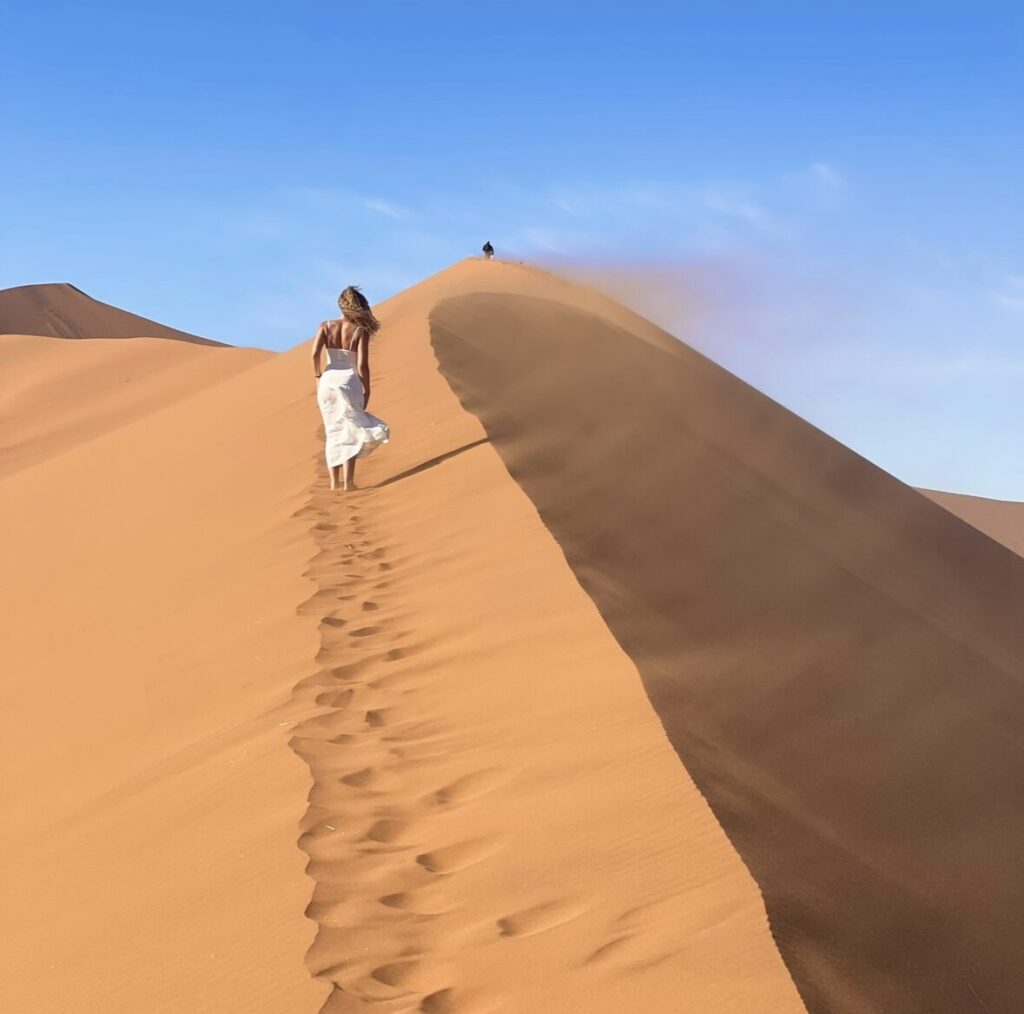 curly haired girl in white flowy dress in Namibia's red dunes 